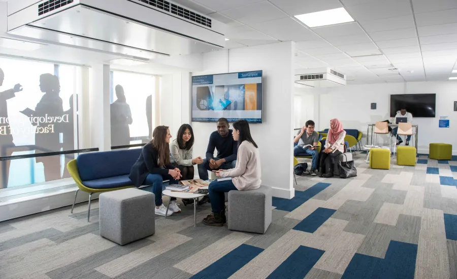 A small group of students sit and chat in a corner of the Business School study space.