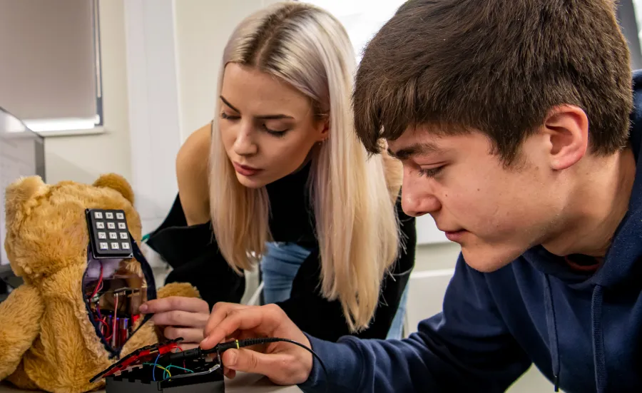 Two electronic engineering students with a teddy in their hands