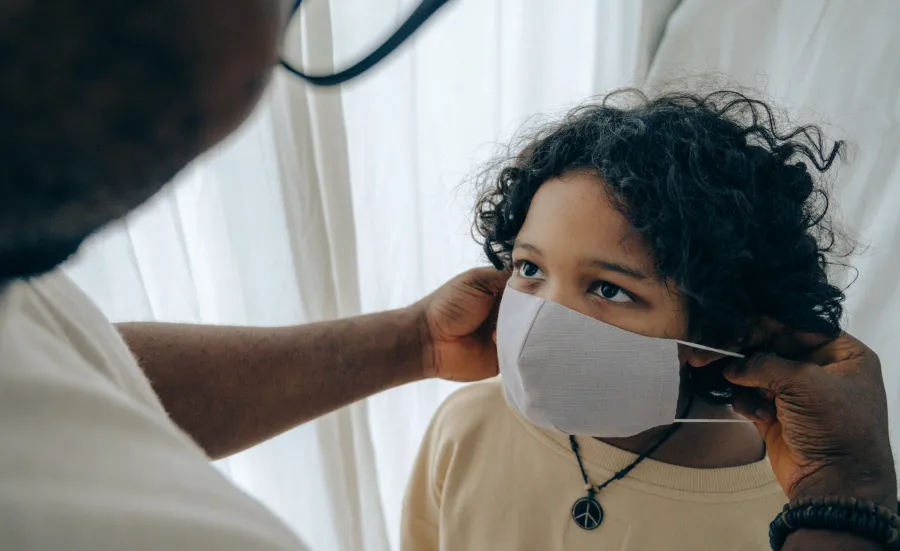A patient looks up as a medical professional puts a clinical mask onto them
