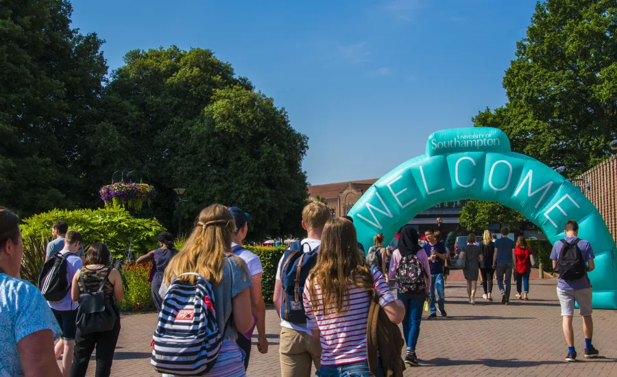 Open Day visitors walking through a large, blue welcome archway at Highfield Campus