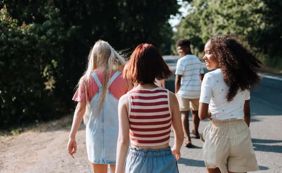 Teenagers walking down a sunny country lane away from the camera