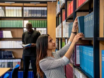 A student looking through bookshelves in the law library collection