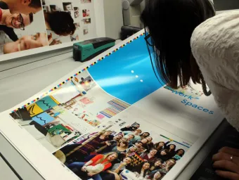A designer closely checks a brightly coloured printer's proof for colour accuracy