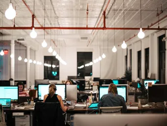 Unsplash image of seated workers using computers, in a modern office with high ceilings