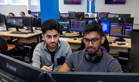 Student and tutor looking at business trading screen.