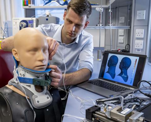 Researcher inserts sensors to measure pressure at the interface between a neck brace and a mannequin head model