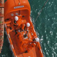 Aerial view of a lifeboat at sea next to a ship