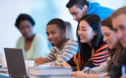 Female student at laptop surrounded by classmates.