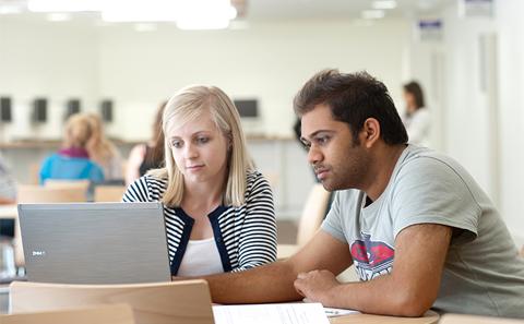 two students around a laptop
