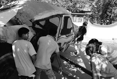 People moving an old car