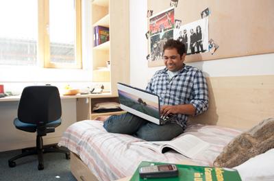 Student studying in his room with a laptop