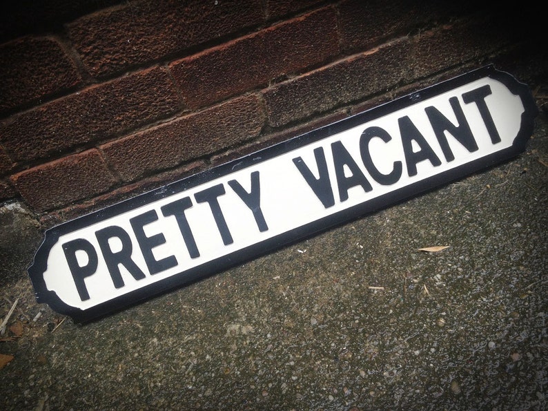 Pretty vacant street sign left on a pavement by a brick wall