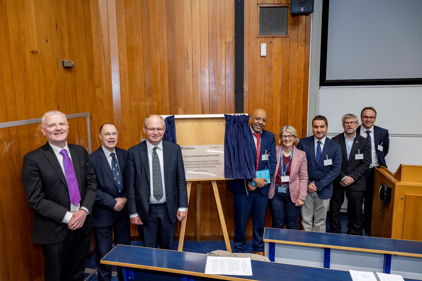 People stood smiling around plaque unveiling