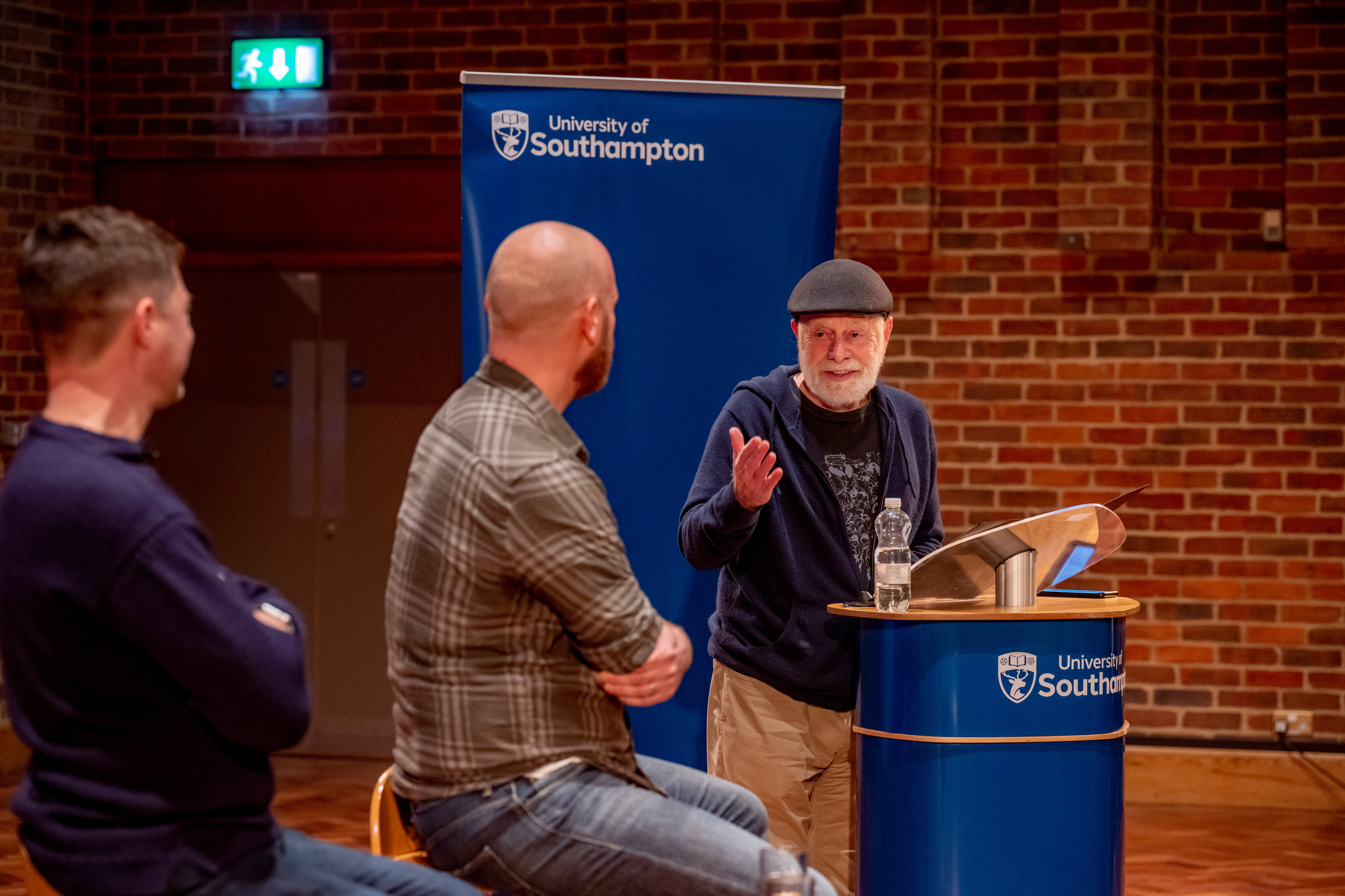 Roger saying his speech to the audience on stage and looking at Will as he watches on