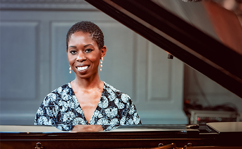 woman sat at piano smiling
