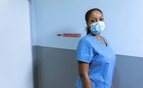 A&E nurse next to 'emergency' sign