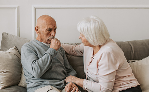 Older man coughing into his hand