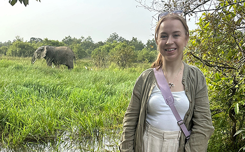 Woman in front of trees and elephant