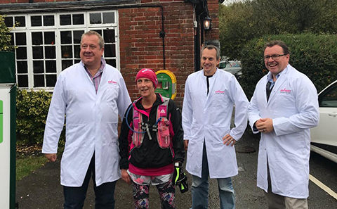 Three men in lab coats with woman in running gear