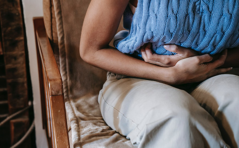 Woman sat down holding her stomach