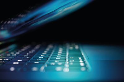 A close up photo of a laptop keyboard, lit by the screen in a dark room