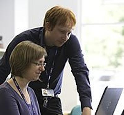 Two people talking in front of a computer