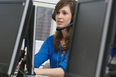 A member of our ServiceLine team looking at a monitor and wearing a headset