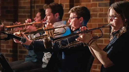 Four students playing trumpets