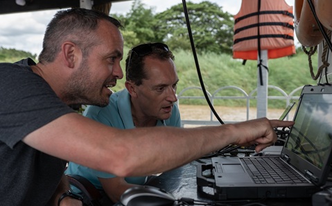 Professors Julian Leyland and Steve Darby looking at a laptop, surrounded by greenery.