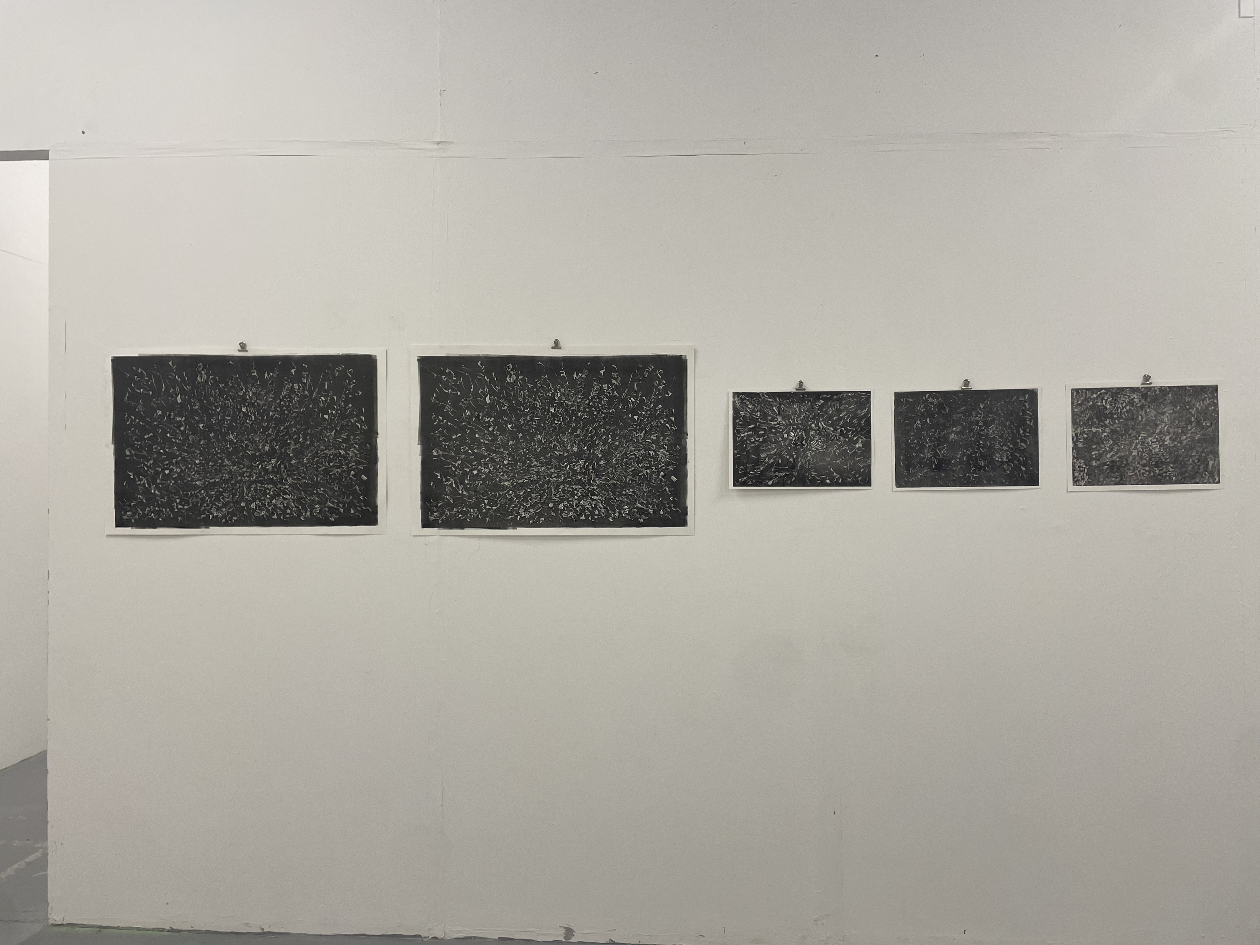 A series of five black-and-white abstract prints with intricate patterns arranged in a row on a plain white wall.