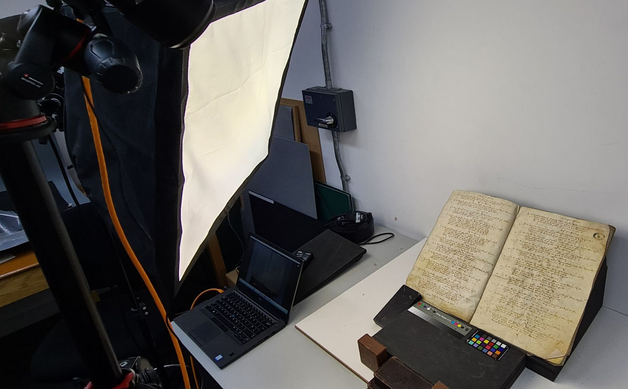 Historic handwritten document on a stand being lit by a diffused lamp