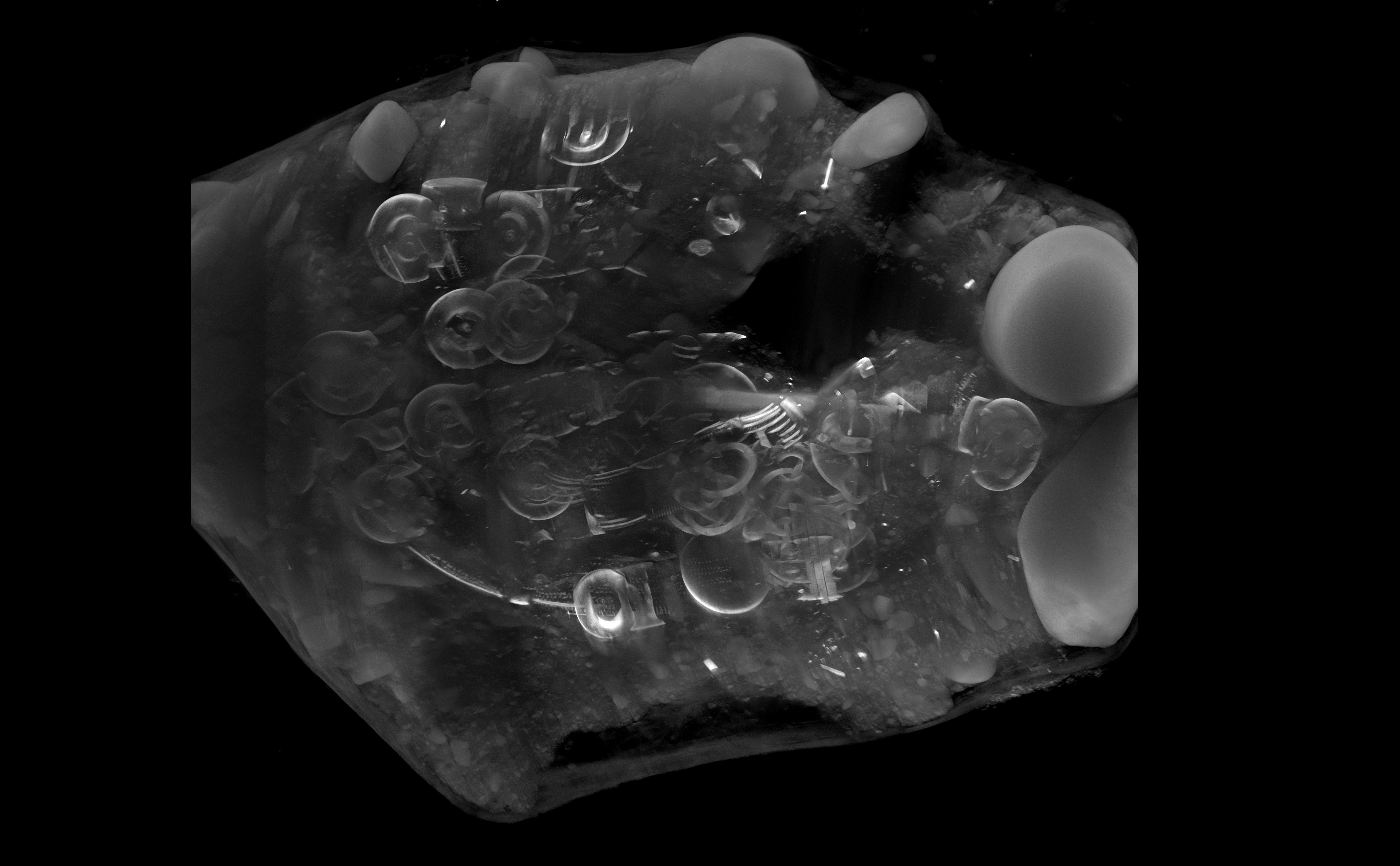 A black and white x-ray image of an archaeological hoard showing artefacts within a block of soil