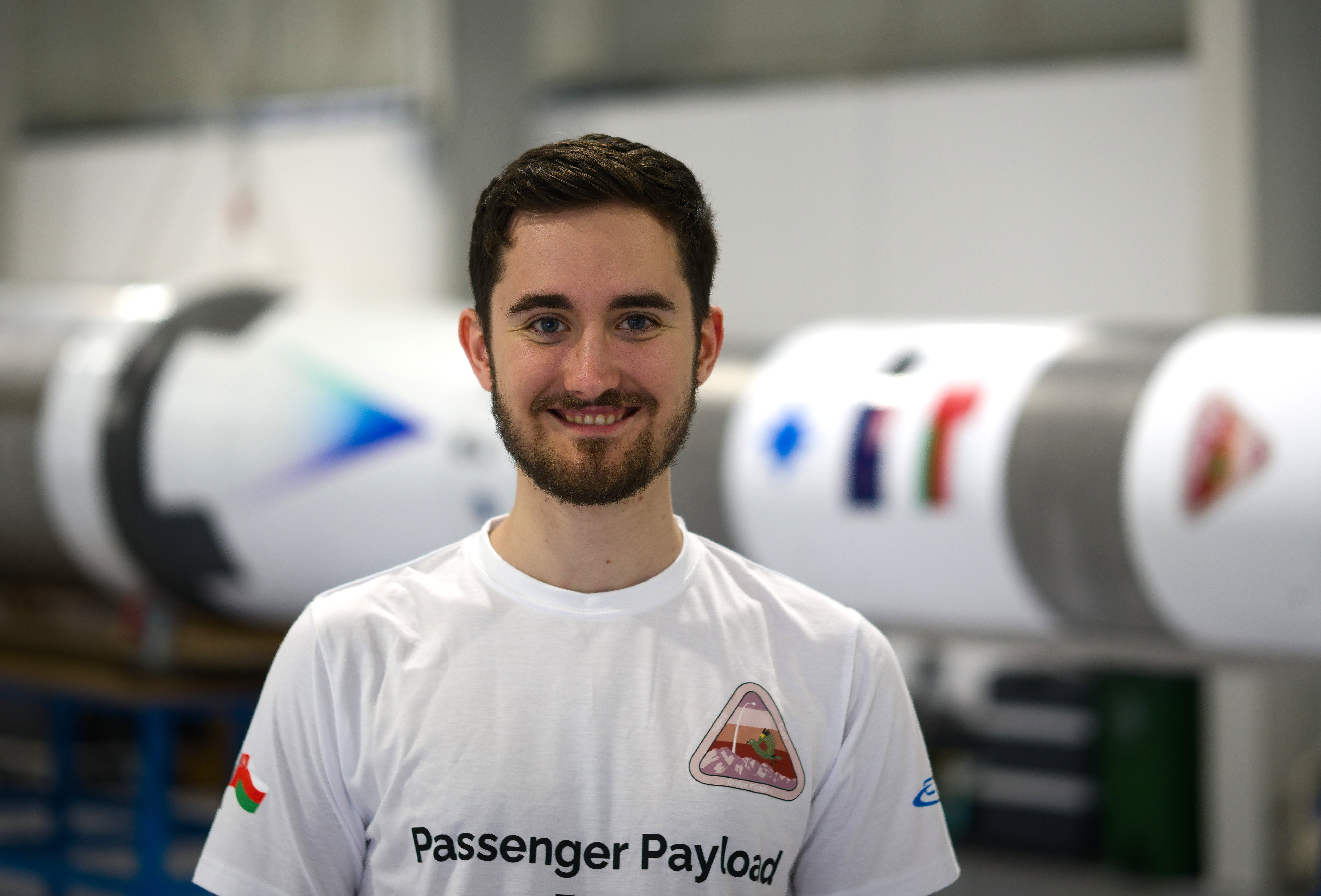 Alejandro Parra Pintado in white tshirt standing in front of a white rocket