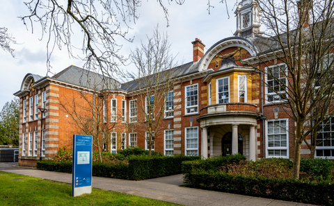 Front facade of Avenue Campus, a building shown during daylight surrounded by greenery