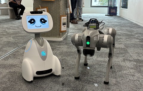 A robot with a screen for a face and a robotic dog standing side by side 