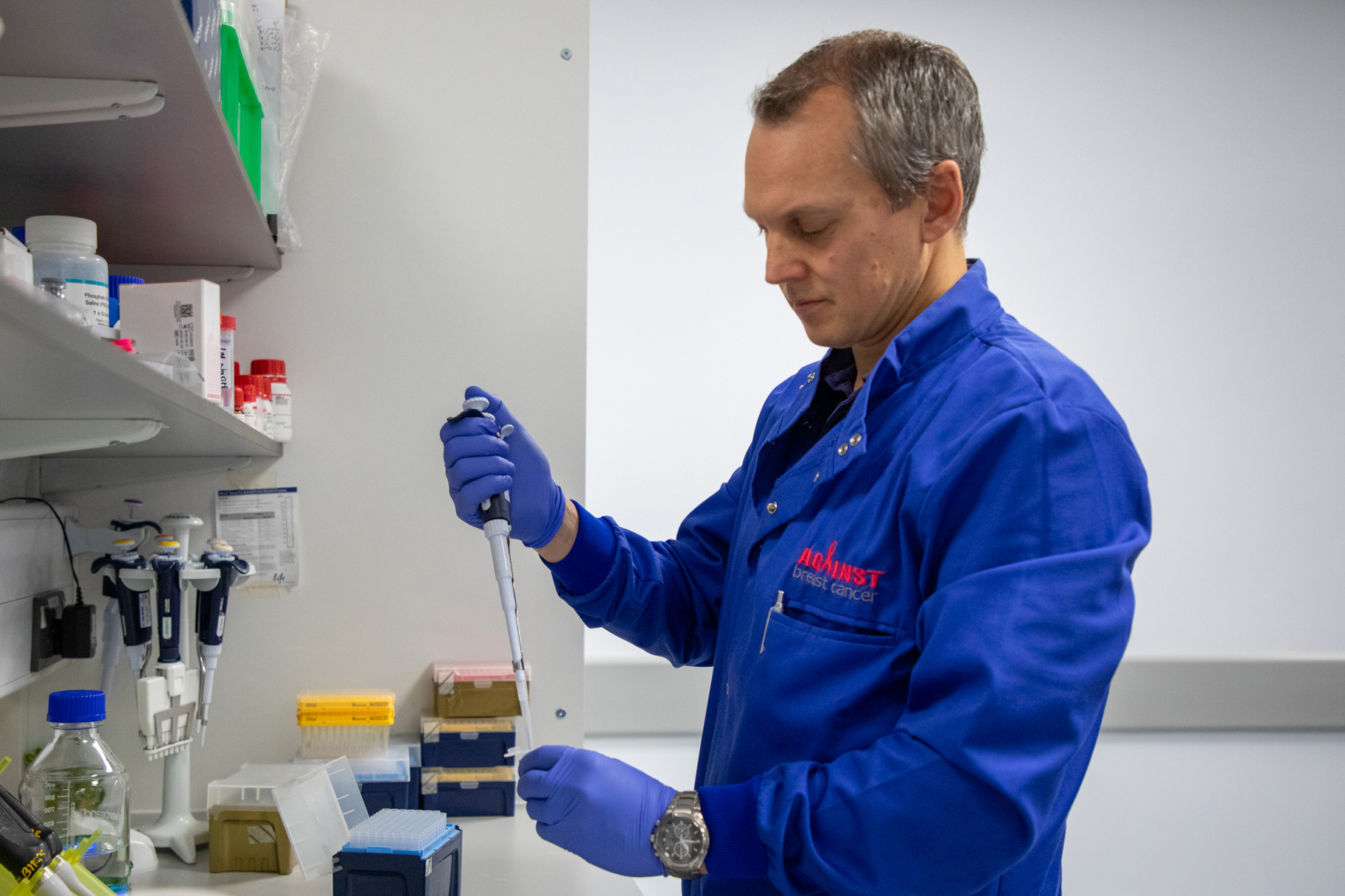 A scientist wearing a blue lab coat branded