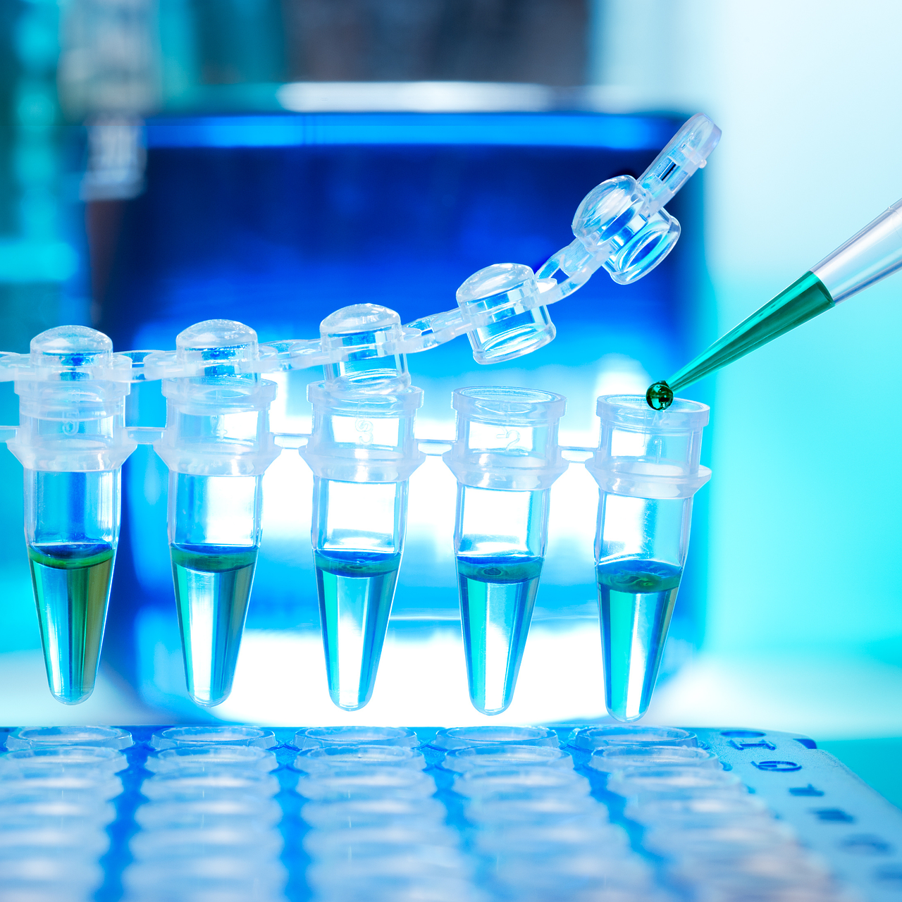 A laboratory scene showing a pipette dispensing a green liquid into a row of transparent microcentrifuge tubes partially filled with blue-green solution, set against a blue scientific background.