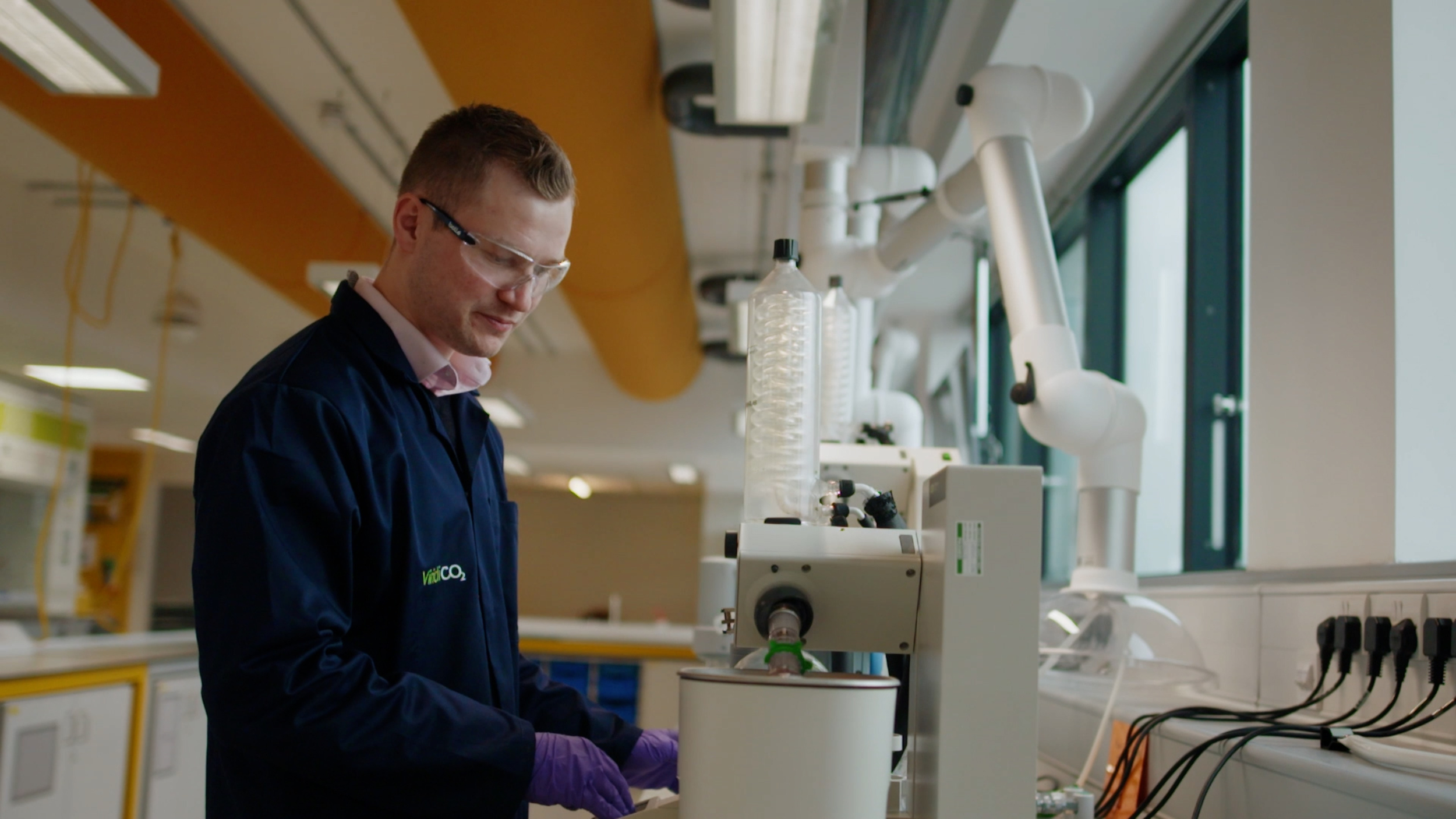 Dr Dan Stewart from spinout company ViridiCO2 in blue labcoat working on drilling machine