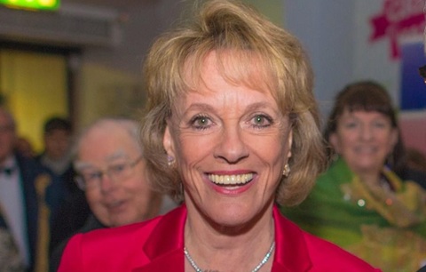 Head and shoulders photo of a smiling woman wearing a red blazer and a silver necklace