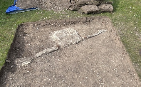 A close up of an area of excavated soil, with white piping and a white box exposed in the earth