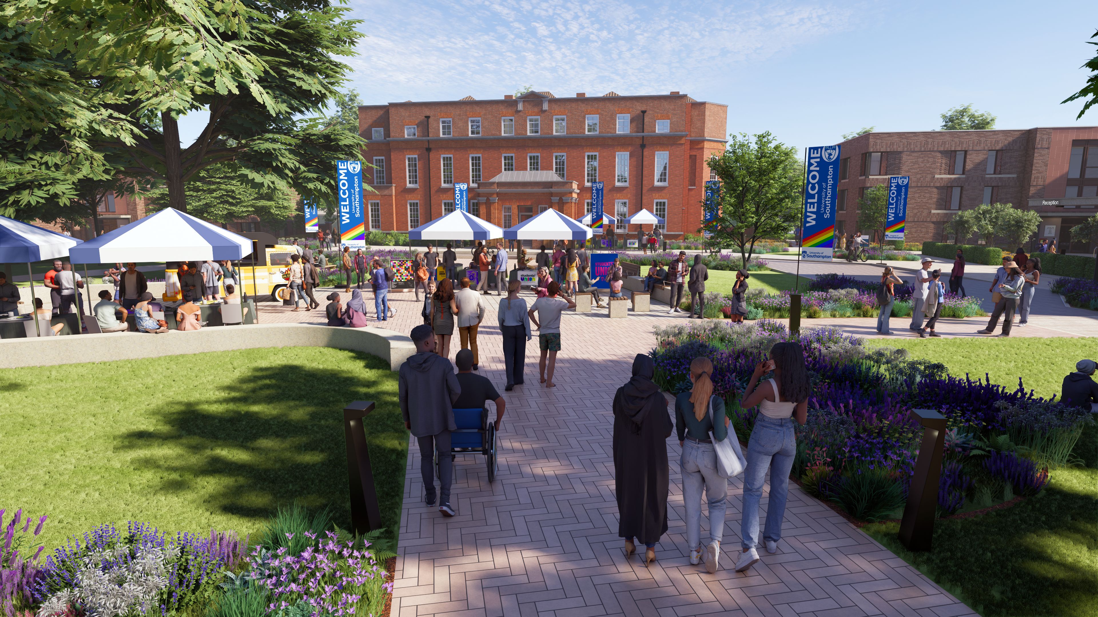 People gathered at an outdoor campus event with tents and banners on a landscaped walkway in front of a large brick building 