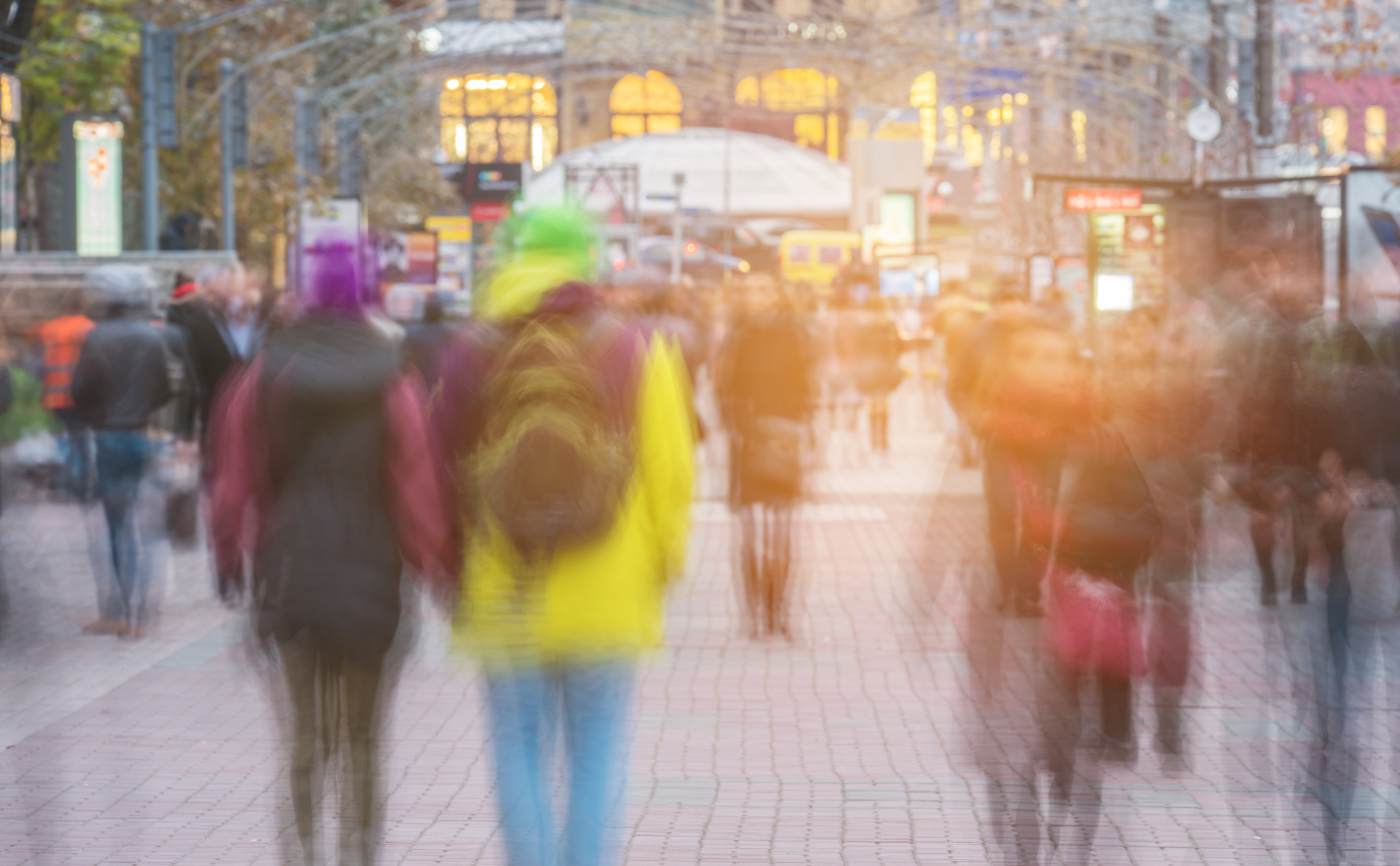 Blurred image of a crowd of people walking away from the camera in a city street