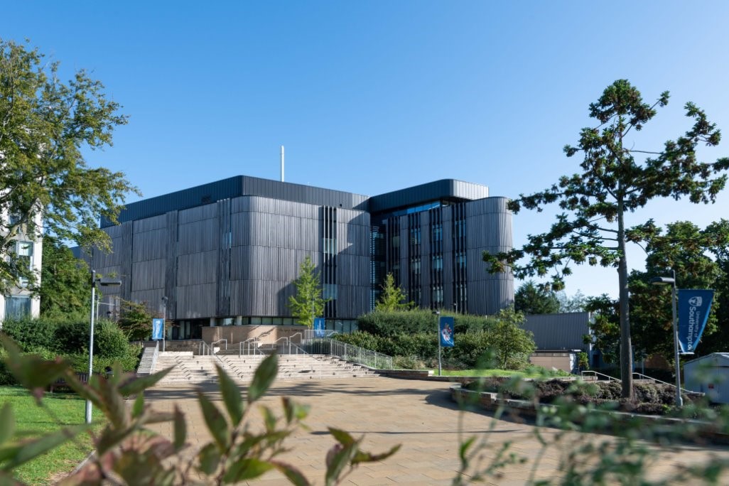A grey building can be seen in the background and it is surrounded by trees