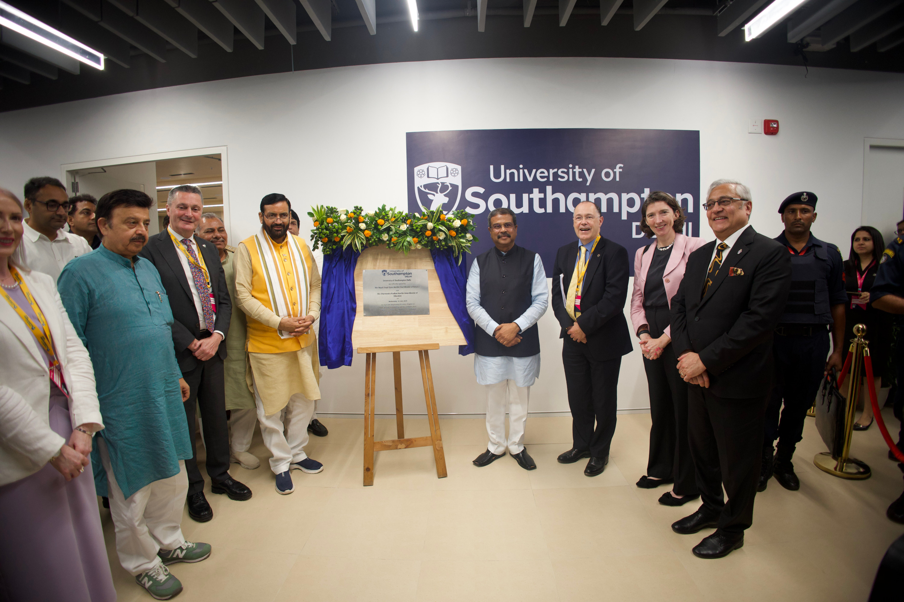 Delegates gather around plaque to celebrate launch of Delhi campus