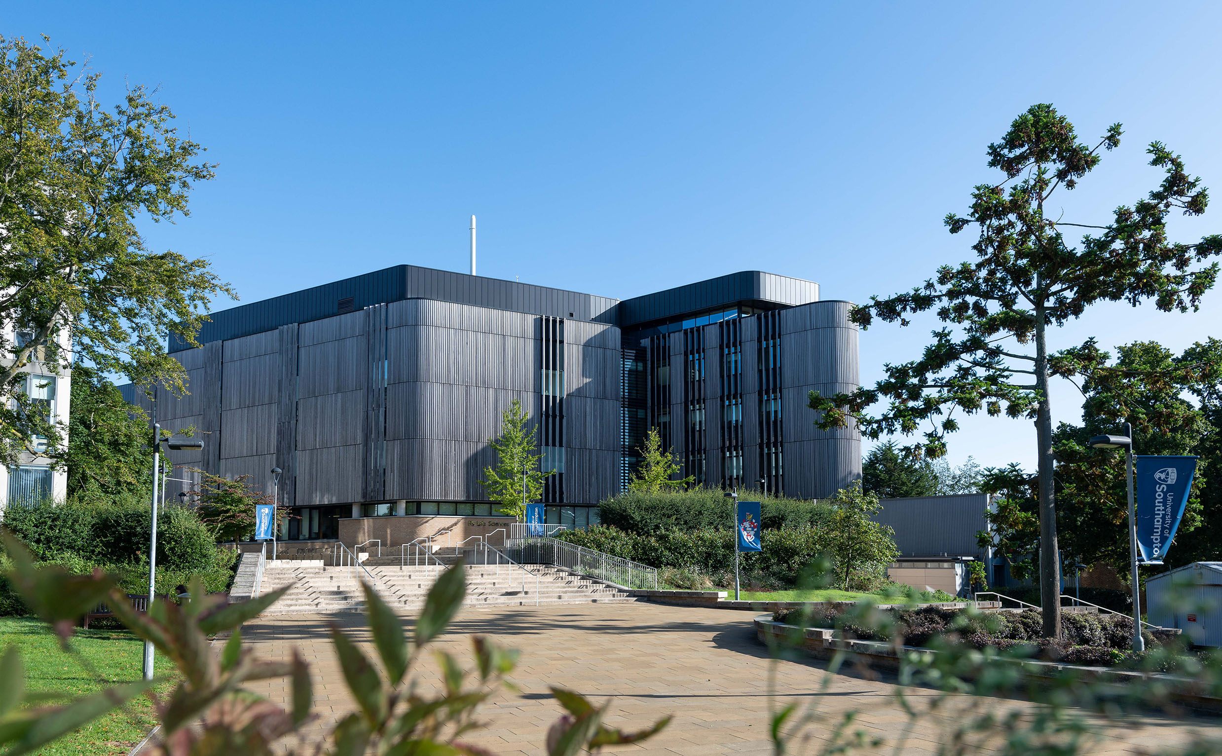 A wide paved pedestrian square area in front of a wooden clad university research building