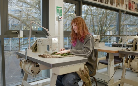 Young woman with long hair sitting at a sewing machine