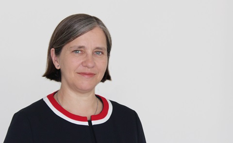 Head and shoulders image of a woman with short straight hair, wearing a black jacket with white and red trim.