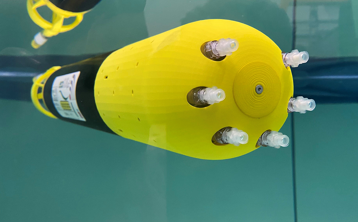 Yellow and black mini-sub which is cylinder shaped and rounded at one end with six tube-like syringes protruding to collect water.
