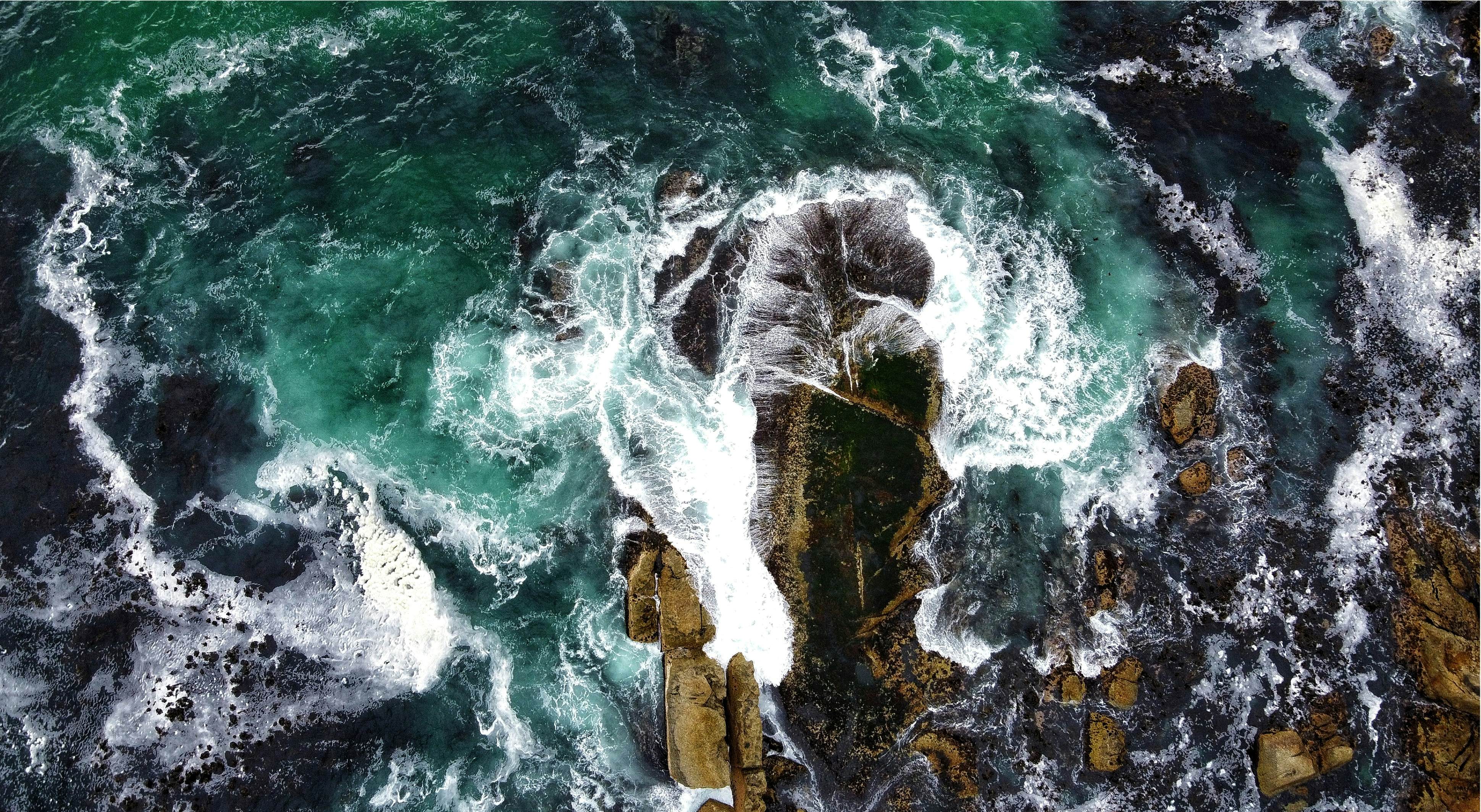 Picture taken from the air showing waves crashing on splashing rocks 