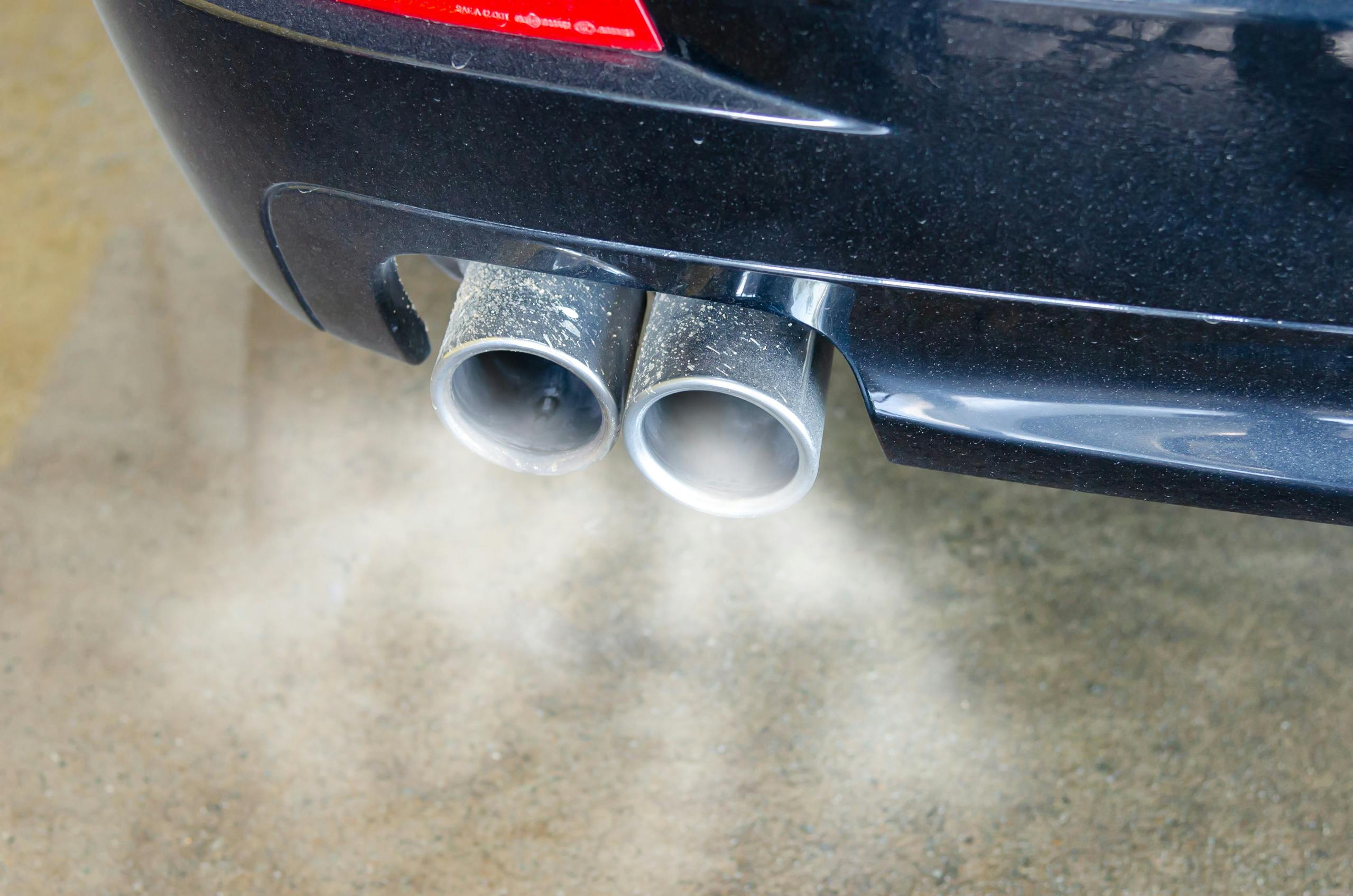 Exhaust fumes coming from the twin exhaust pipes of a black car